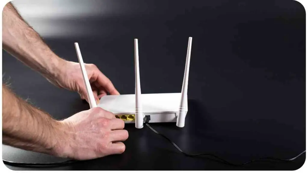 a person is holding a white router on a black surface.