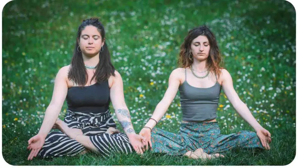 two individuals sitting in the grass doing yoga